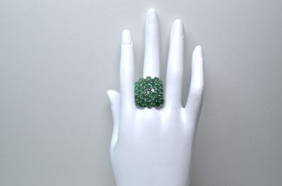 une main blanche sur laquelle est posée une bague verte