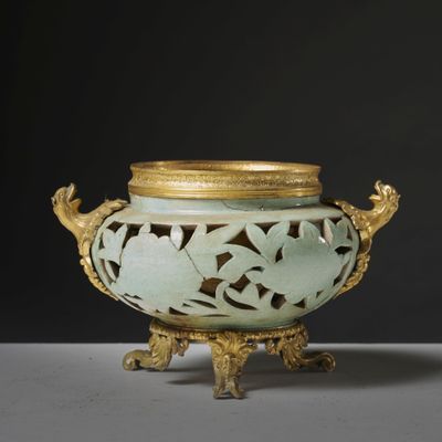 un vase vert avec un couvercle doré posé sur une table