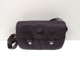 sac à bandoulière en cuir violet avec des anses en cuir noir sur fond blanc