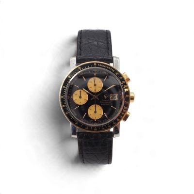 l'image d'une montre noire et or sur une surface blanche
