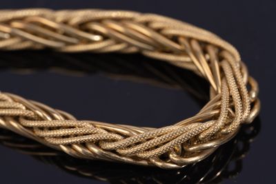 a close up of a gold bracelet on a black surface