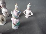 five figurines of women in different colors on a gray surface