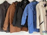 quatre manteaux accrochés au mur à côté d'un porte-manteau