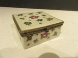 une petite boîte blanche décorée de fleurs, posée sur une table