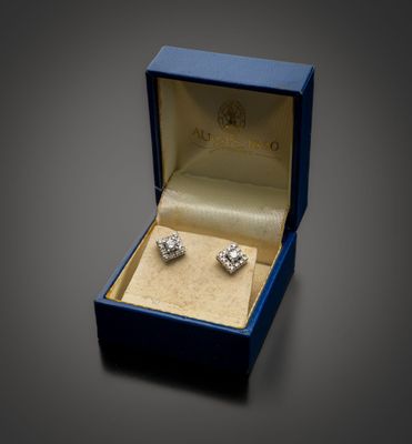 une photo d'une paire de boucles d'oreilles en diamant dans un écrin bleu