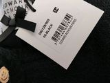 the label on a black sweater is attached to a white tag