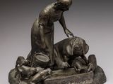 statue en bronze représentant une femme agenouillée près d'un chien, sur un rocher