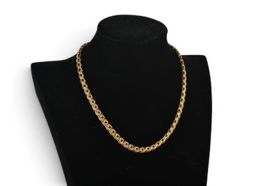 a gold chain necklace on a black mannequin