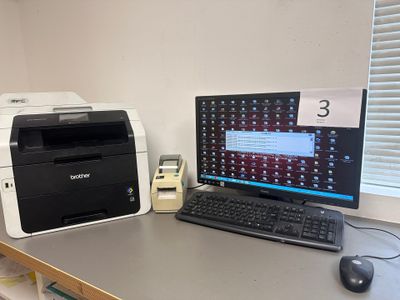 un ordinateur et une imprimante posés sur un bureau dans une pièce