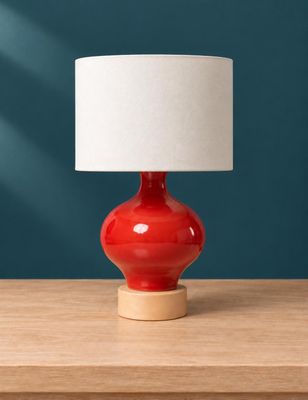 un gros plan d'une lampe de table rouge posée sur une table en bois
