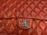 a red chanel bag sitting on a table next to a pair of shoes