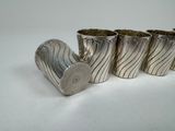 four silver vases sitting on a white surface