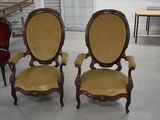 une paire de chaises anciennes dans une pièce, avec une table et des chaises en arrière-plan