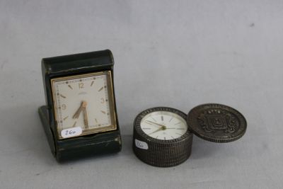 une petite horloge posée à côté d'une pièce de monnaie sur une table