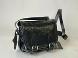 le petit sac en cuir noir est posé sur une surface blanche