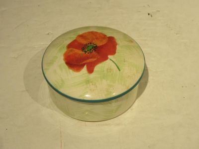 une petite boîte en verre ornée d'une fleur rouge
