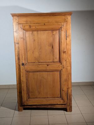 une armoire en bois dans un coin d'une pièce au sol carrelé