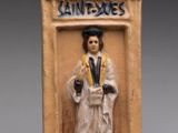 une photo d'une figurine en céramique représentant une femme en toge de remise des diplômes