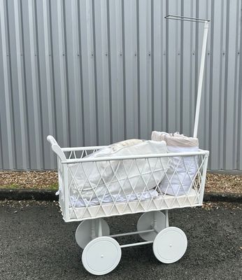 une poussette blanche avec un bébé dedans dans la rue