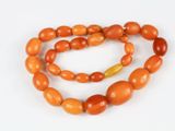 un gros plan sur un collier de perles orange posé sur une surface blanche