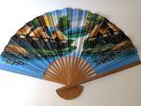 a fan with a painting on it hanging on a wall