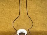 une image représentant une lampe blanche suspendue à une chaîne sur un fond jaune