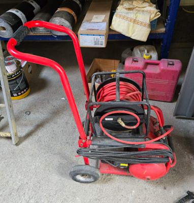 a red hand truck with a hose on it in a garage