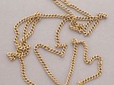 a close up of a gold chain with a heart on it