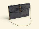 the black clutch bag is on a white surface with a chain around it