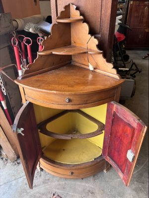 une armoire d'angle en bois surmontée d'un miroir