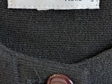 a close up of a black shirt with a gold button on it
