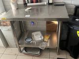 une cuisine équipée d'une table en inox et d'une poubelle noire