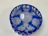 a blue glass bowl with white flowers on it