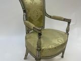 un fauteuil recouvert de tissu vert, avec un dossier et des accoudoirs recouverts de tissu doré