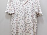 a white shirt with floral print on it hanging on a hanger