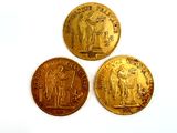 three gold coins sitting on top of each other on a white surface