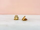 a pair of gold earrings sitting on top of a marble counter