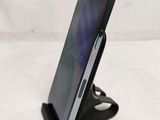 a close up of a cell phone on a stand on a white surface