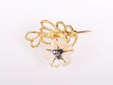 un gros plan d'une broche en forme de fleur en or sertie de pierres bleues