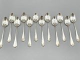 six cuillères en argent sont alignées sur une surface grise