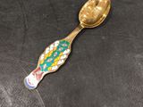 a gold spoon with a colorful fish design on it