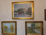 paintings hanging on the wall of a room with pictures on the wall