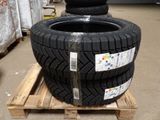 quatre pneus empilés sur une palette dans un entrepôt