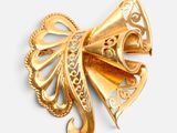 an image of a gold colored brooch with a bow on it