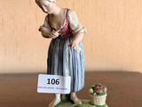 une figurine représentant une femme avec un panier de fleurs posé sur une table