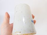 une personne tenant une tasse à la main, posée sur une surface blanche