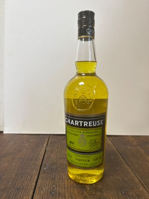un gros plan sur une bouteille de Chartreuse posée sur une table en bois