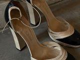pair of black and white high heeled shoes sitting on a cement floor