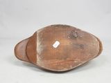 an old wooden bowl with a tag on it sitting on a white surface