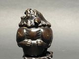 a small statue of a frog sitting on top of a ball